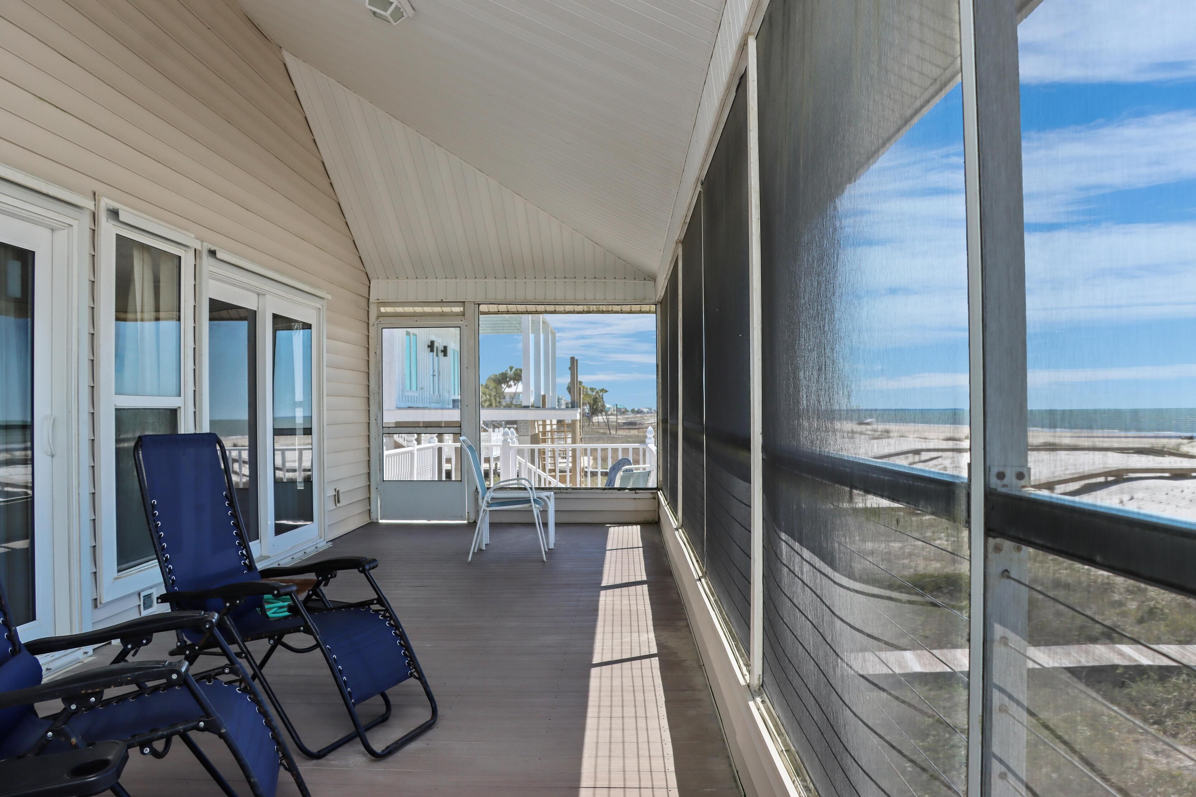 Ein überdachter Außenbereich mit Blick auf den Strand, ausgestattet mit einer Sitzecke inklusive Stühle und Tisch.