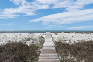 A wooden boardwalk leading to a beach with sand dunes and sparse vegetation. - Road's End (Port St. Joe)