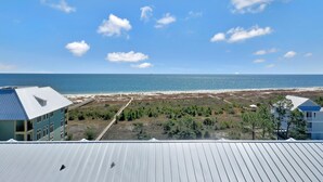 Blick auf die Küste mit Strand, einem Gebäude mit blauem Dach und strahlend blauem Himmel.