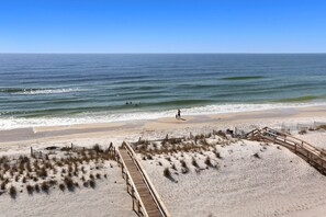 A beach with a wooden boardwalk leading to the shore, sandy dunes, and the ocean. - Five on the Beach (Port St. Joe)