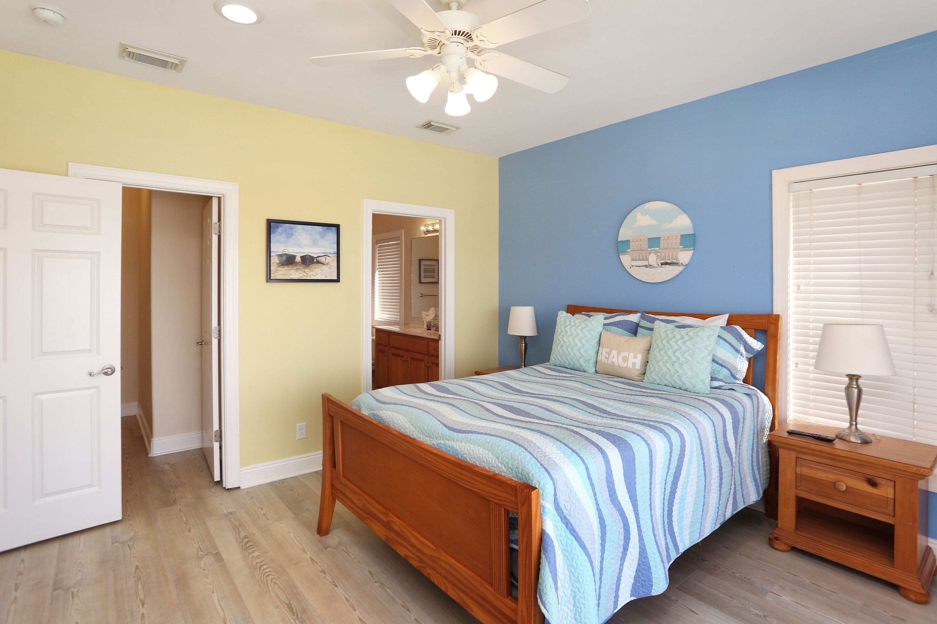 A bedroom with a wooden bed, a nightstand, a ceiling fan, and a window with blinds.