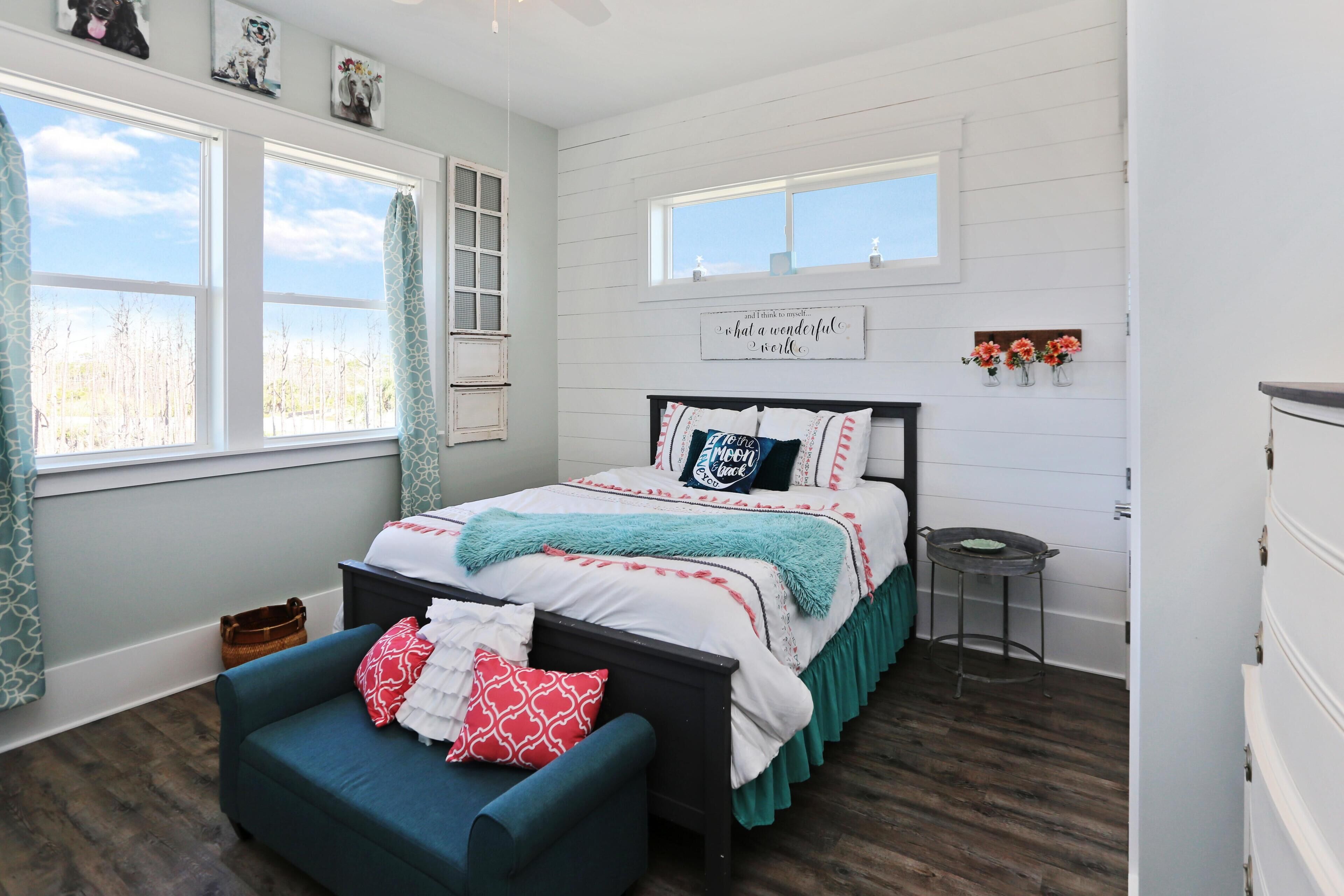A bedroom with a bed, a chair, a small table, and a window.
