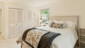 Une chambre à coucher avec un lit, une table de chevet, une fenêtre et un placard.