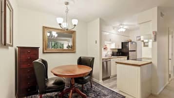 A compact kitchen with white cabinets, a stainless steel refrigerator, and a microwave.
