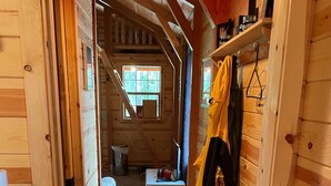 Un estrecho pasillo de madera con alfombra, paredes de madera y una ventana al final.