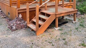 Una cabaña de madera con un porche y una escalera que lleva a la entrada.