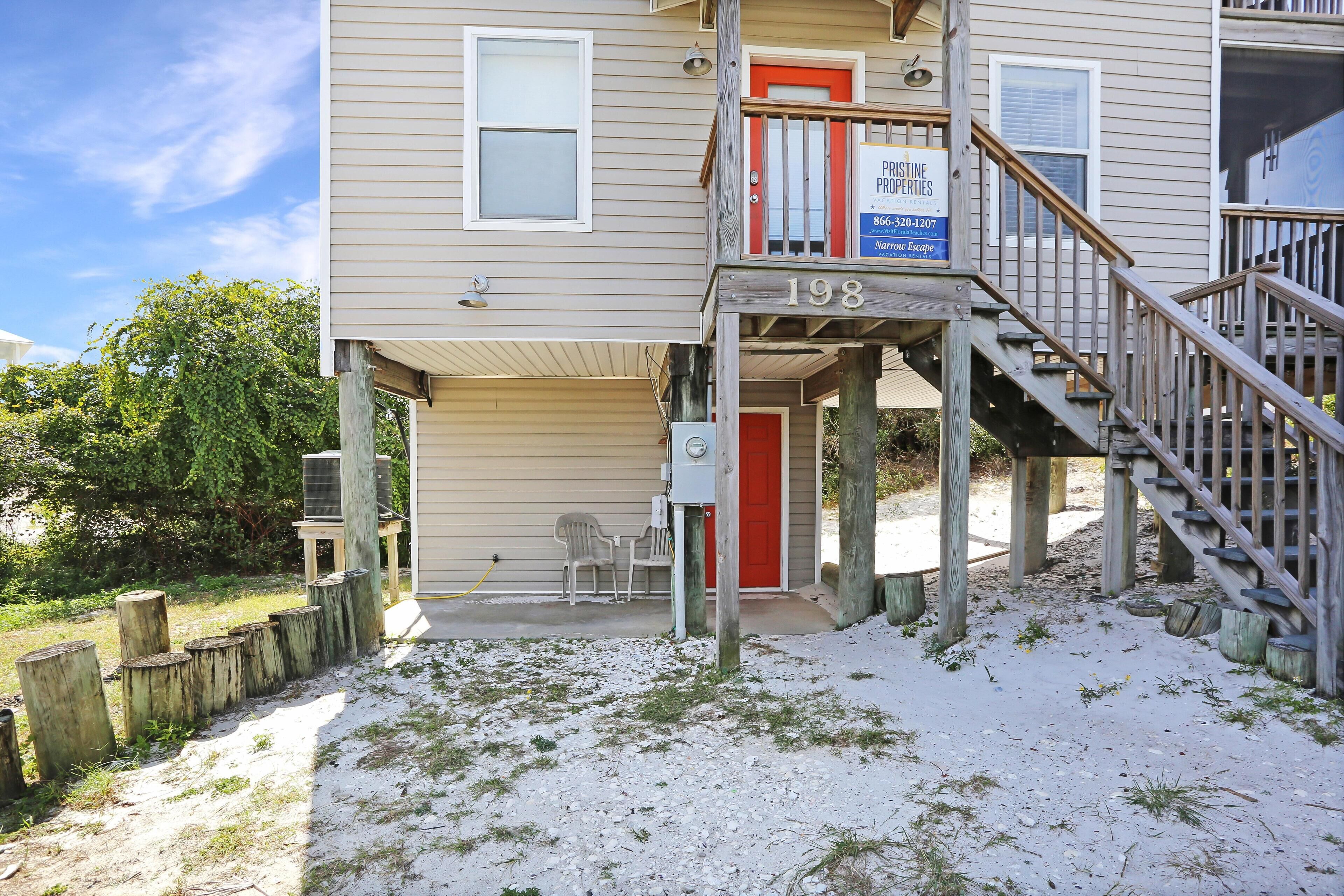 A two-story house with a wooden staircase and a red door.
