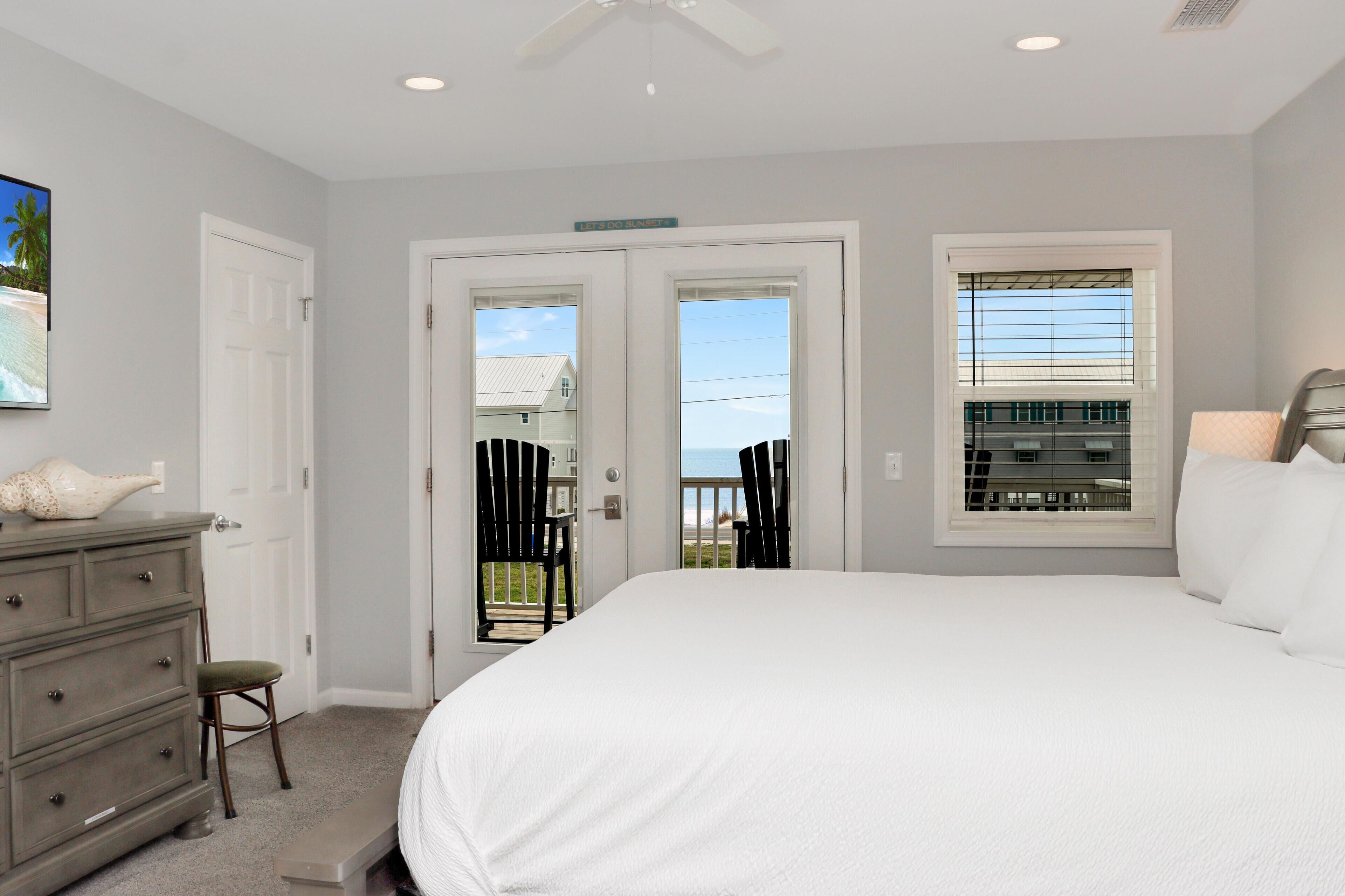A bedroom with a large bed, a dresser, a chair, and a window with blinds.