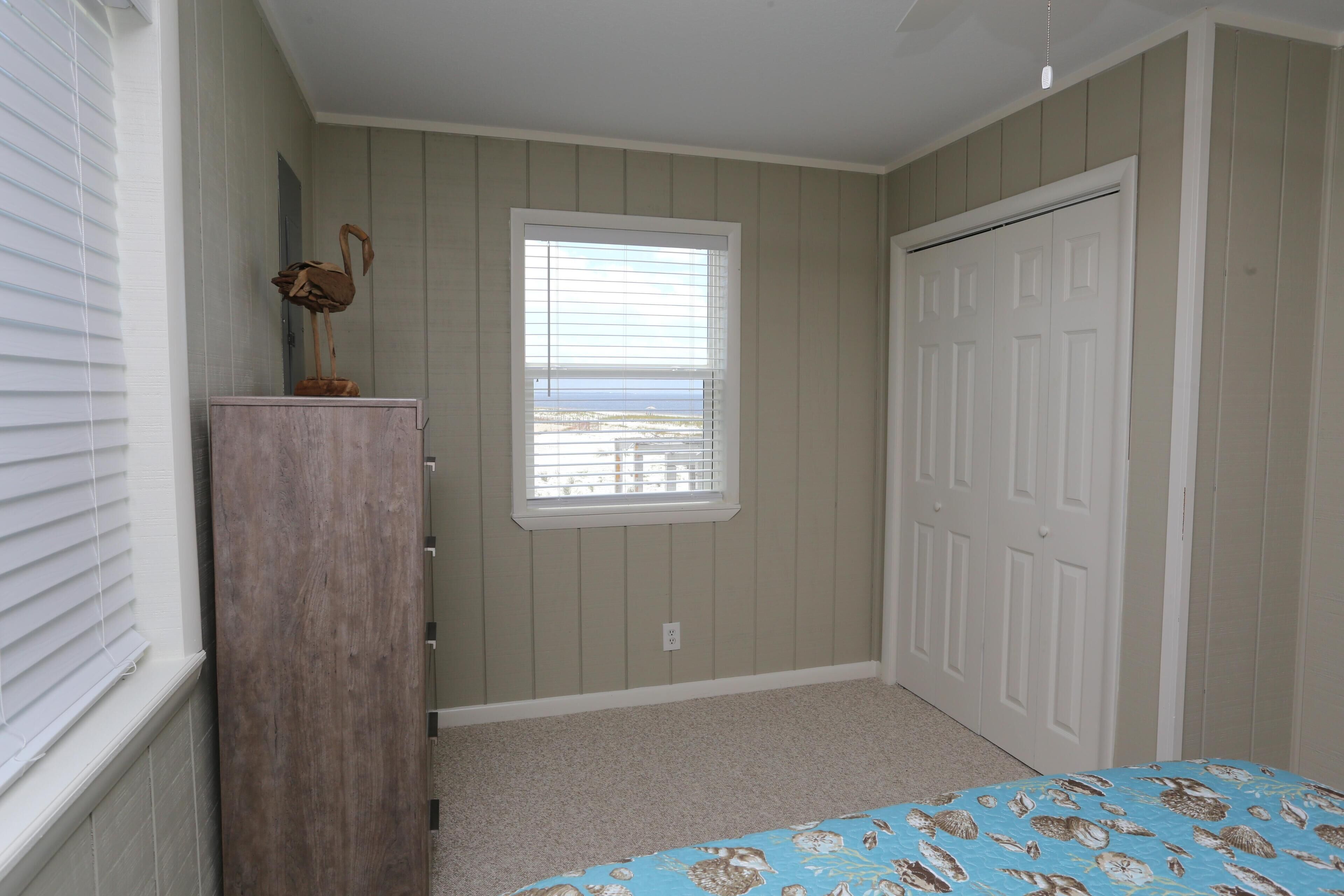 A bedroom with a window, a door, and a bed with a patterned bedspread.