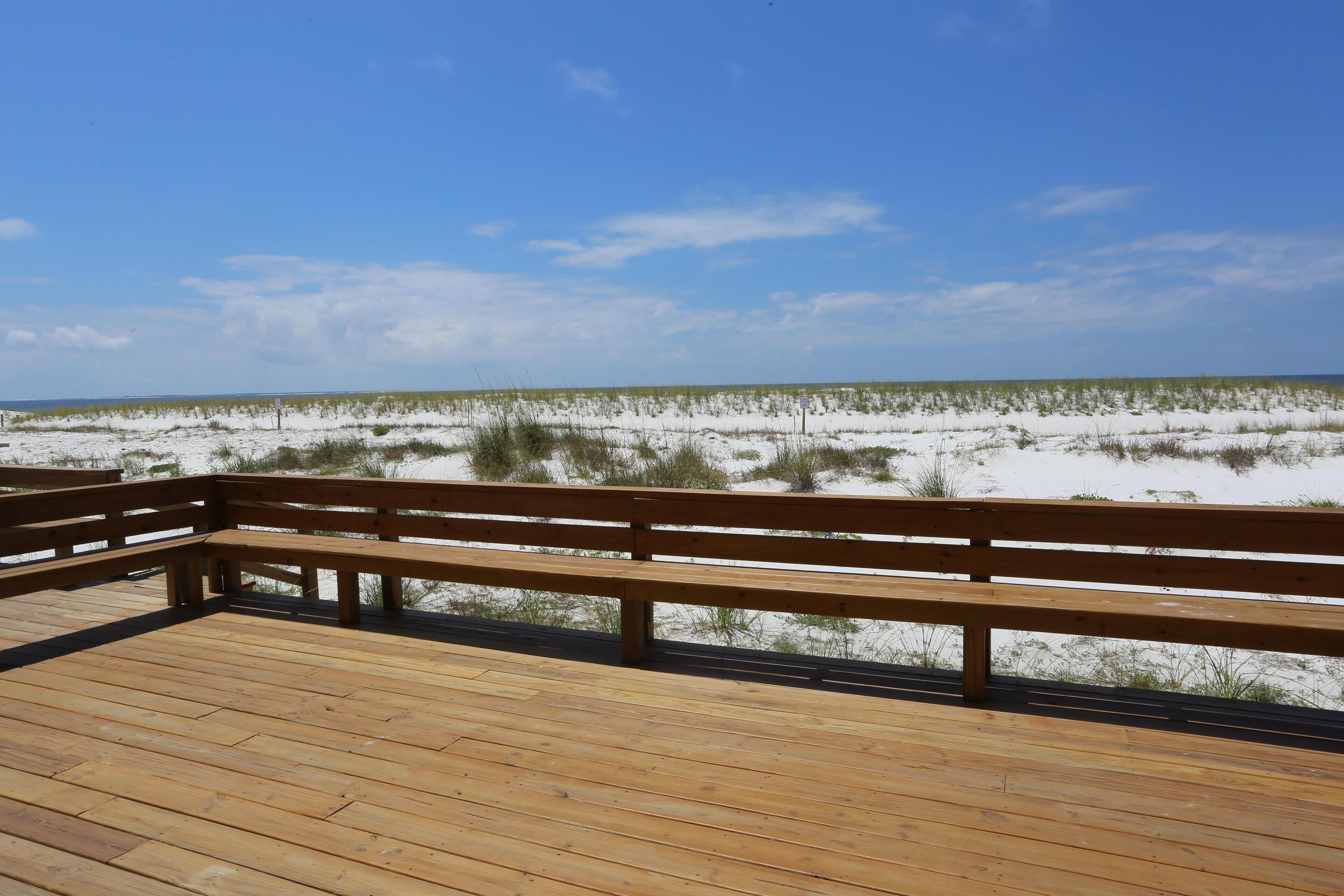 Une terrasse en bois offrant une vue sur une plage et des dunes.
