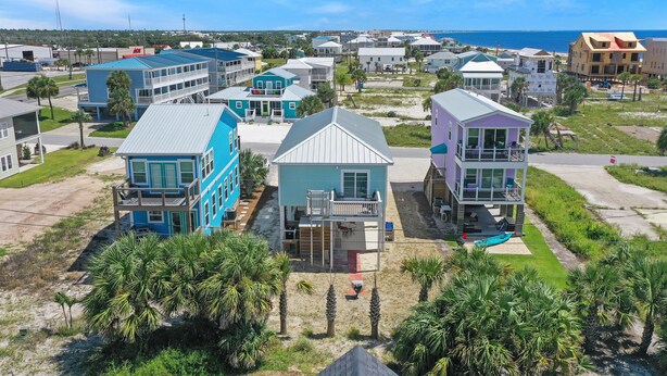 Un quartier résidentiel situé sur la côte, avec des immeubles à plusieurs étages, dont une maison bleue remarquable dotée d’un balcon et une maison blanche avec une terrasse couverte.