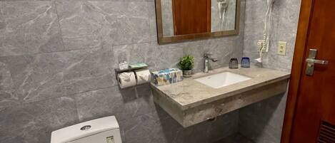 A bathroom with a toilet, sink, and mirror.