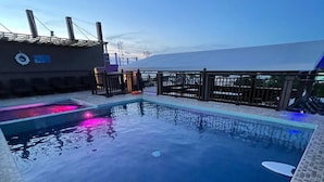 Une piscine bordée de carreaux, un poste de surveillance pour les sauveteurs et une vue sur les environs.