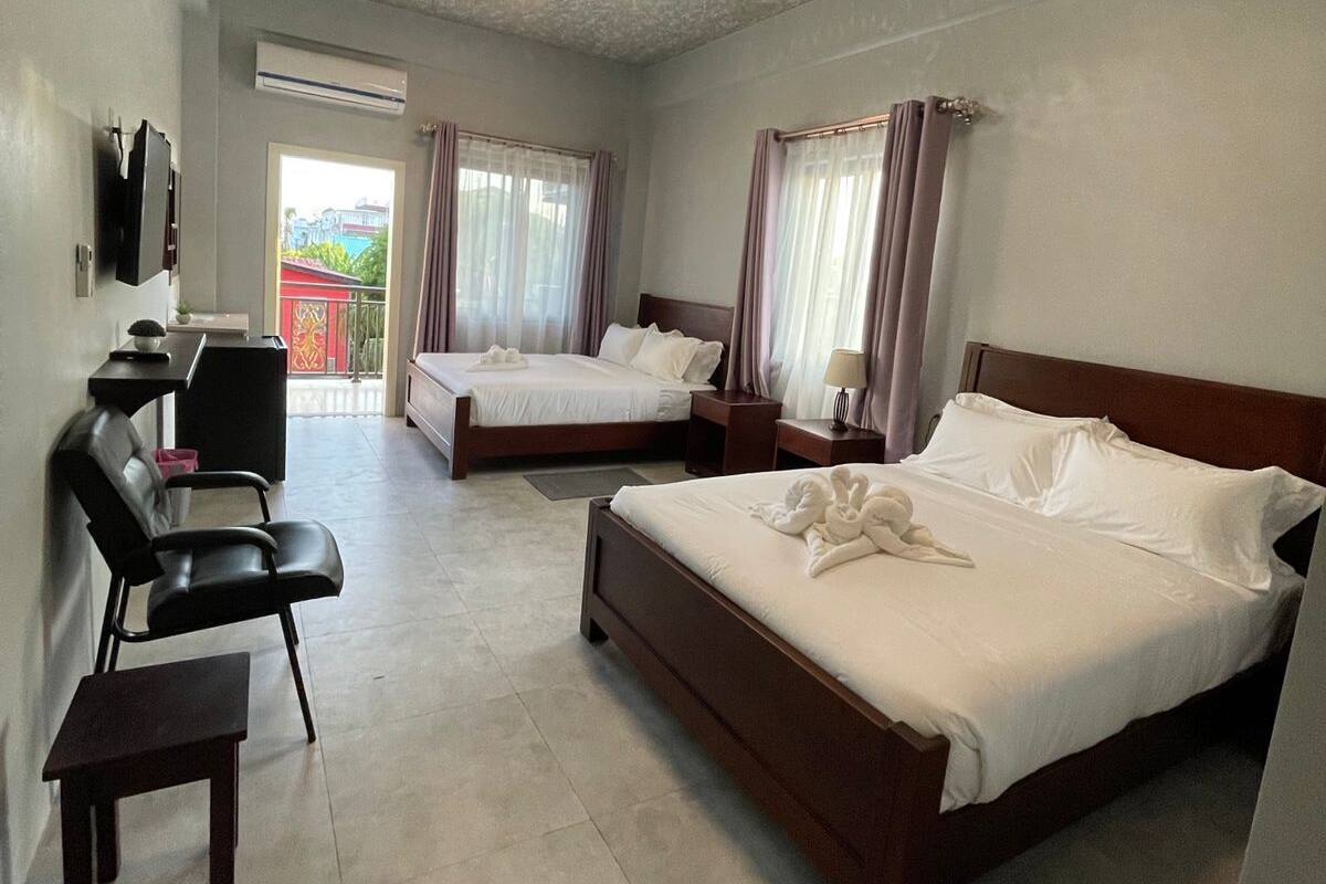 Ein Hotelzimmer mit zwei Betten, einem Schreibtisch, einem Sessel und einem Fernseher.