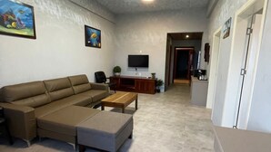 Un salon comprenant un canapé d’angle, une table basse et un téléviseur à écran plat fixé au mur.