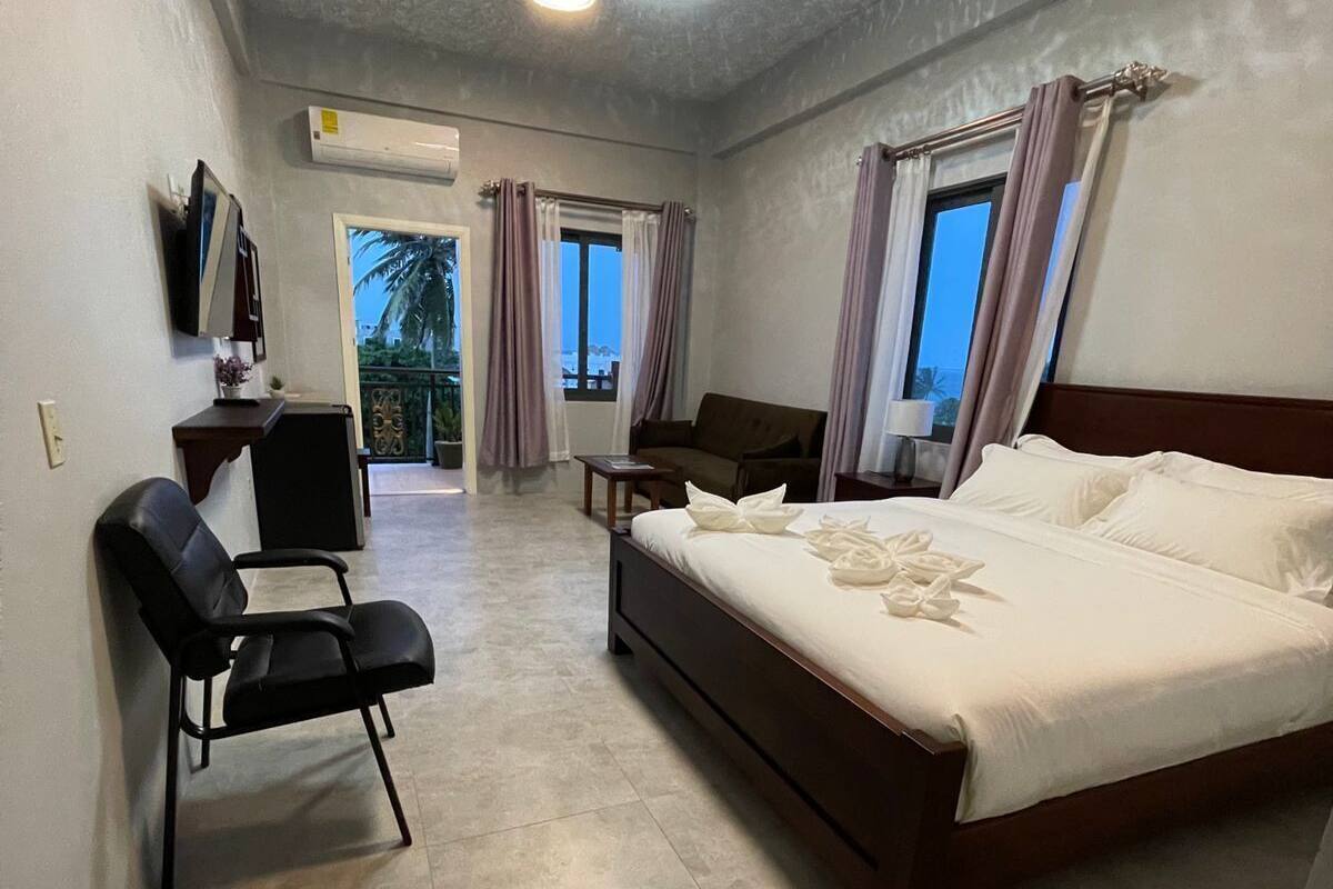 Ein Hotelzimmer mit Bett, Schreibtisch, Stuhl, Fernseher und Deckenventilator.