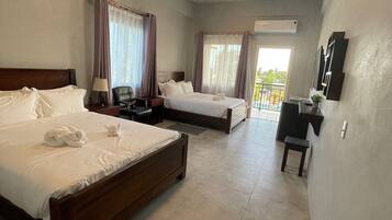 A hotel room with two beds, a desk, a chair, and a small table.