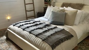 A bedroom with a bed, pillows, a blanket, a ladder, a wall-mounted picture, and a window. - Cozy Cottage Cabin with Wood Burning Fireplace - Pet Friendly! Charming Updates! (Cloudcroft)