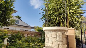 Un bac à fleurs en pierre avec un palmier, une statue et un bâtiment en arrière-plan.