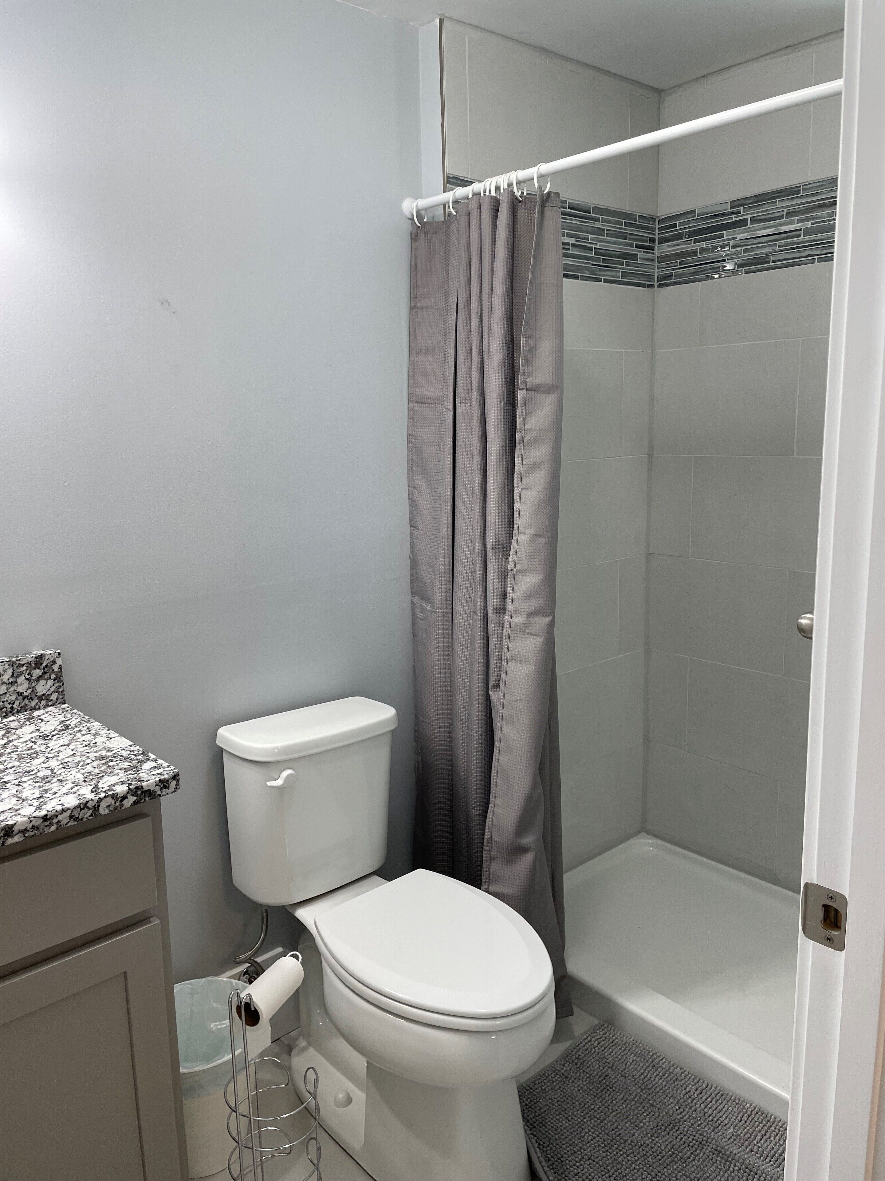 Un baño con inodoro, ducha con puerta de vidrio y encimera de mármol.