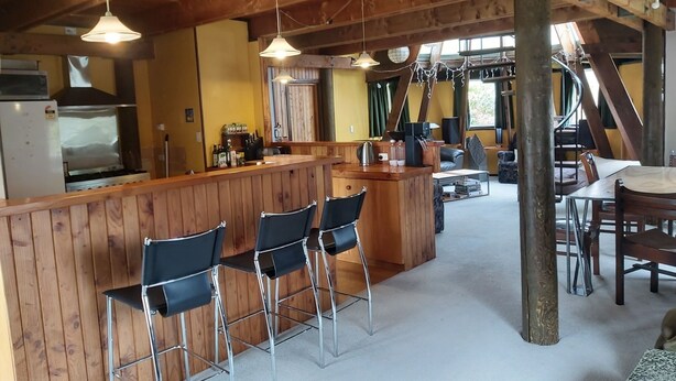 A rustic kitchen with wooden bar stools, a central island, and a dining area with a table and chairs.