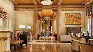 Eine geräumige Lobby mit einem glatten Holzboden, einer prunkvollen Deckenleuchte und einem großen, abstrakten Gemälde an der Wand.