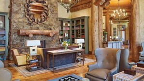 Ein rustikales Interieur mit Kamin, Bücherregalen, Ledersesseln und einem Chandelier.