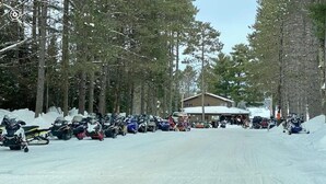 Una strada innevata con motoslitte parcheggiate e un edificio sullo sfondo.