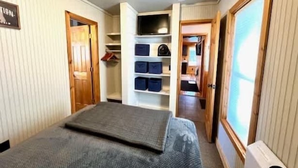 Una stanza compatta con un letto, un armadio a muro e un angolo cottura.