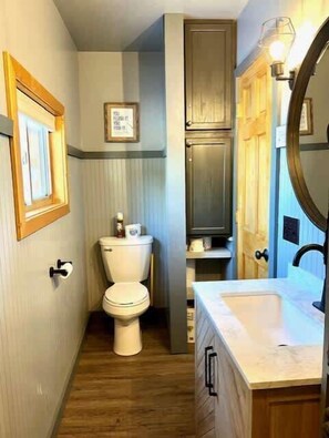Une petite salle de bain comprenant des toilettes, un lavabo et un meuble de rangement.