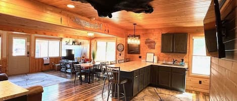 A spacious wooden interior with a large dining area, kitchen, and bar area.