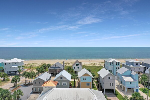 A coastal residential area with houses and a beach in the background.