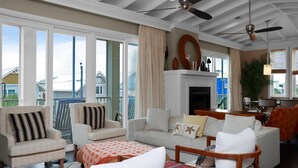 A spacious living room with a fireplace, large windows, and a ceiling fan. - Sammy's Old Place (Port St. Joe)