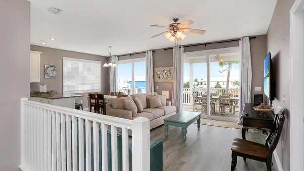 A spacious living room with a large window, a ceiling fan, and a view of the outdoors. - Pearly Shells (Port St. Joe)