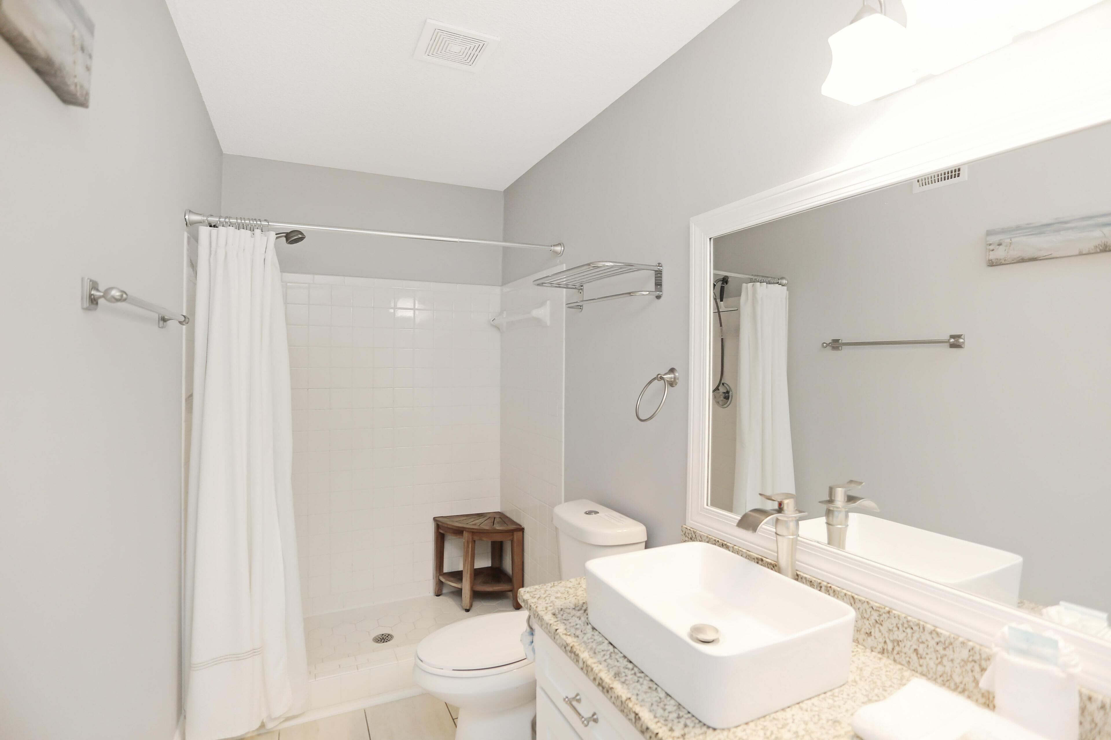 A modern bathroom with a shower, toilet, and a large mirror.
