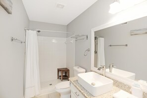 A modern bathroom with a shower, toilet, and a large mirror. - Paradise By The Gulf (Port St. Joe)