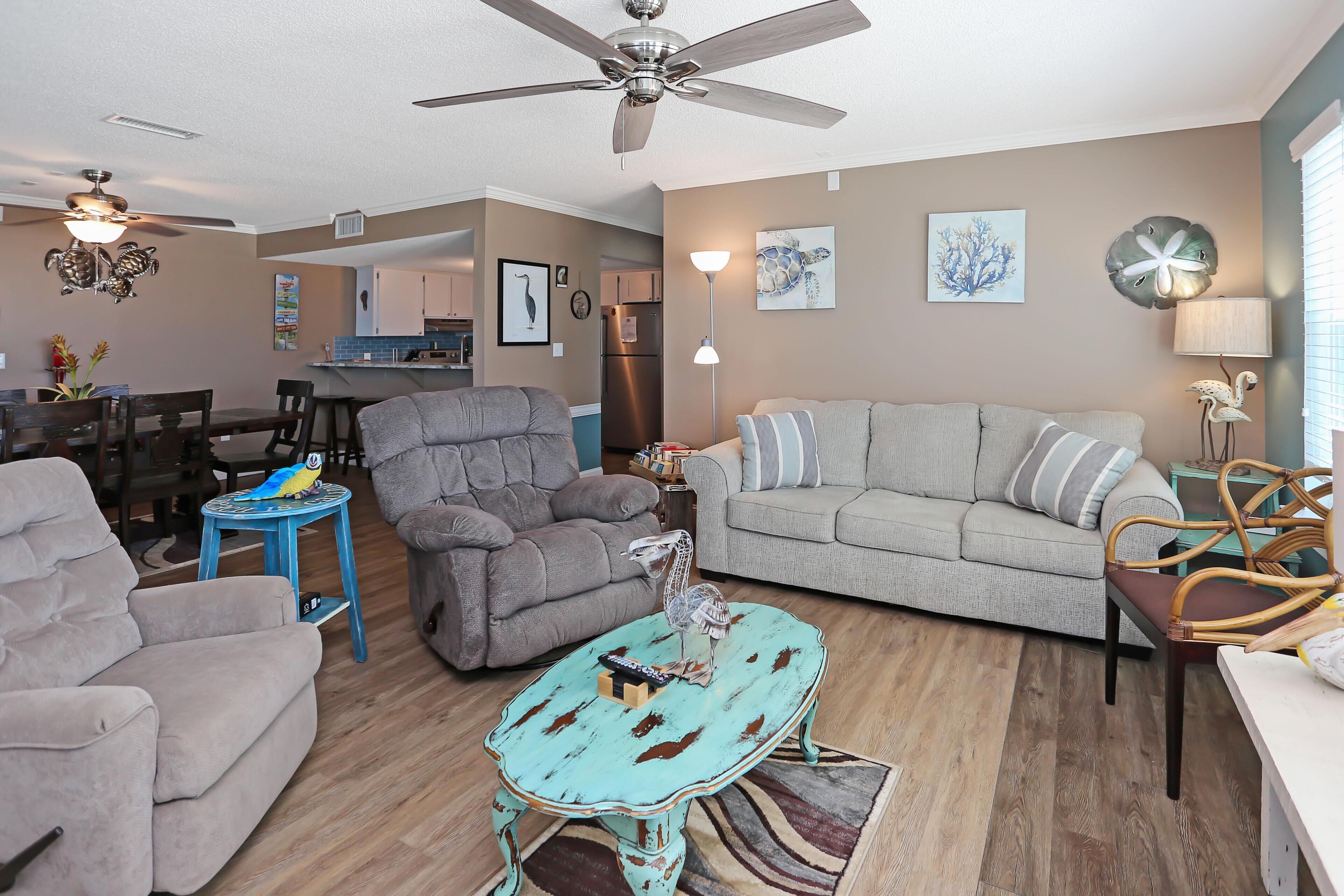 A living room with a grey sofa, a blue coffee table, a grey armchair, and a ceiling fan.