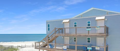 Un bâtiment situé en bord de mer, doté d’une terrasse en bois et d’une enseigne indiquant la présence d’un restaurant.