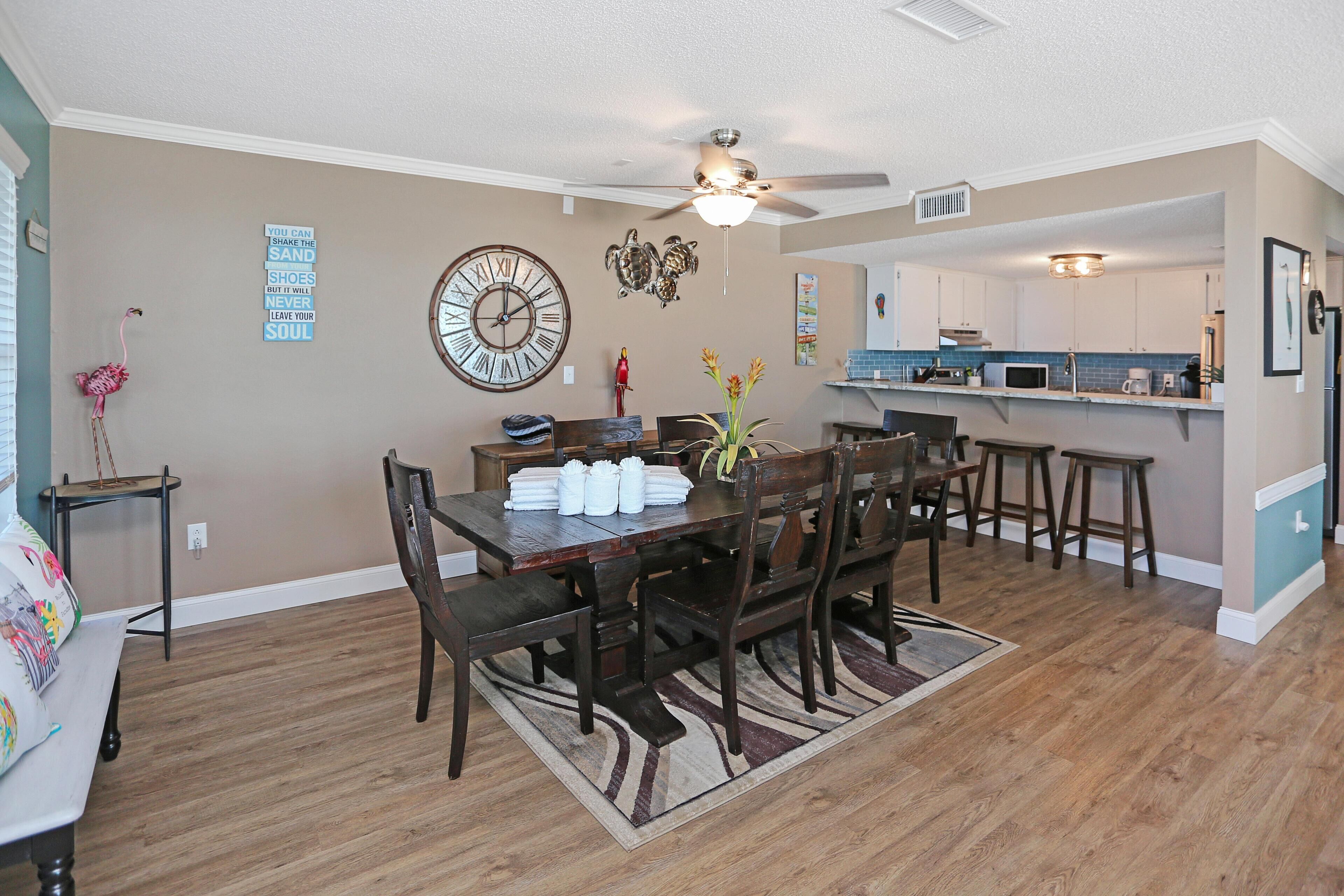 A dining area with a wooden table, chairs, and a decorative clock on the wall.