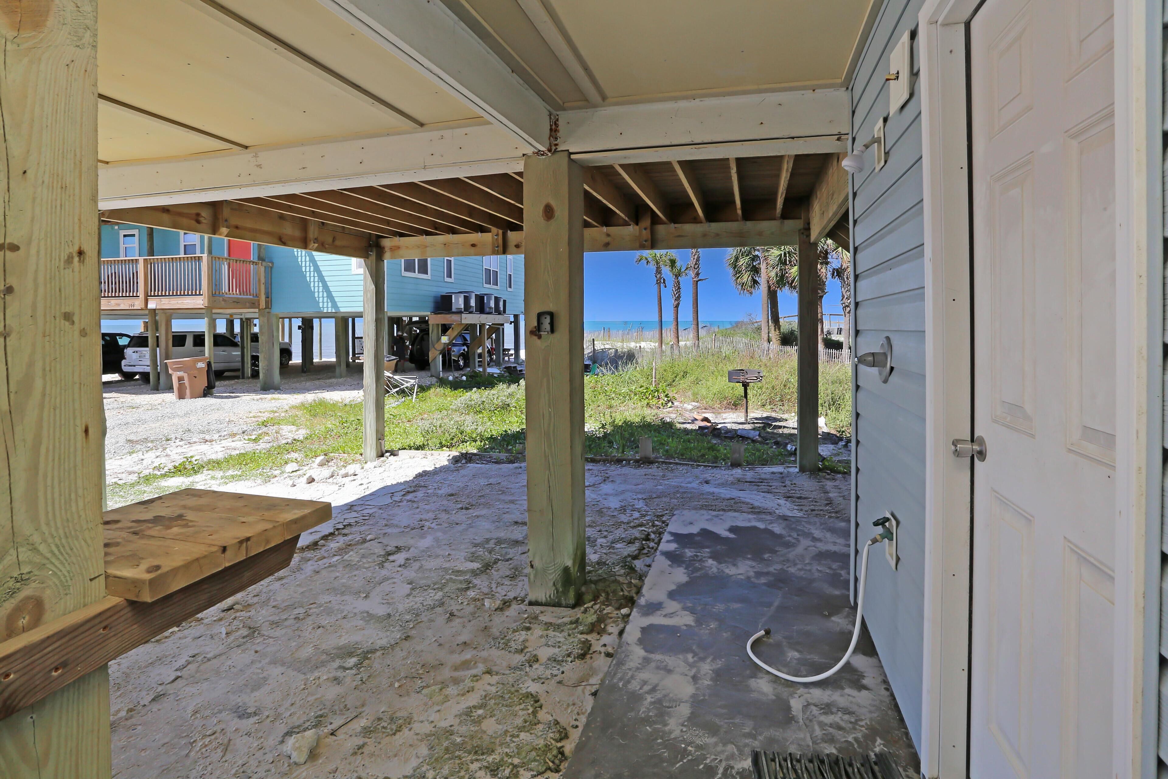 A covered outdoor area with a concrete floor, wooden beams, and a white garage door.