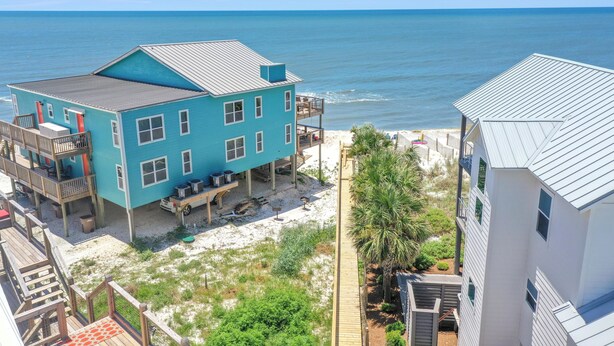 A coastal property with a large blue building, a wooden deck, and a view of the ocean. - Paradise By The Gulf (Port St. Joe)