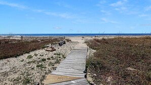 A wooden boardwalk leading to a beach with dunes and sparse vegetation. - Pelican Bend (Port St. Joe)