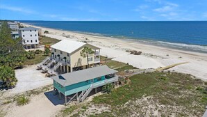 A beachfront property with multiple buildings, including a two-story house with a balcony and a smaller structure with a blue roof. - Pelican Bend (Port St. Joe)