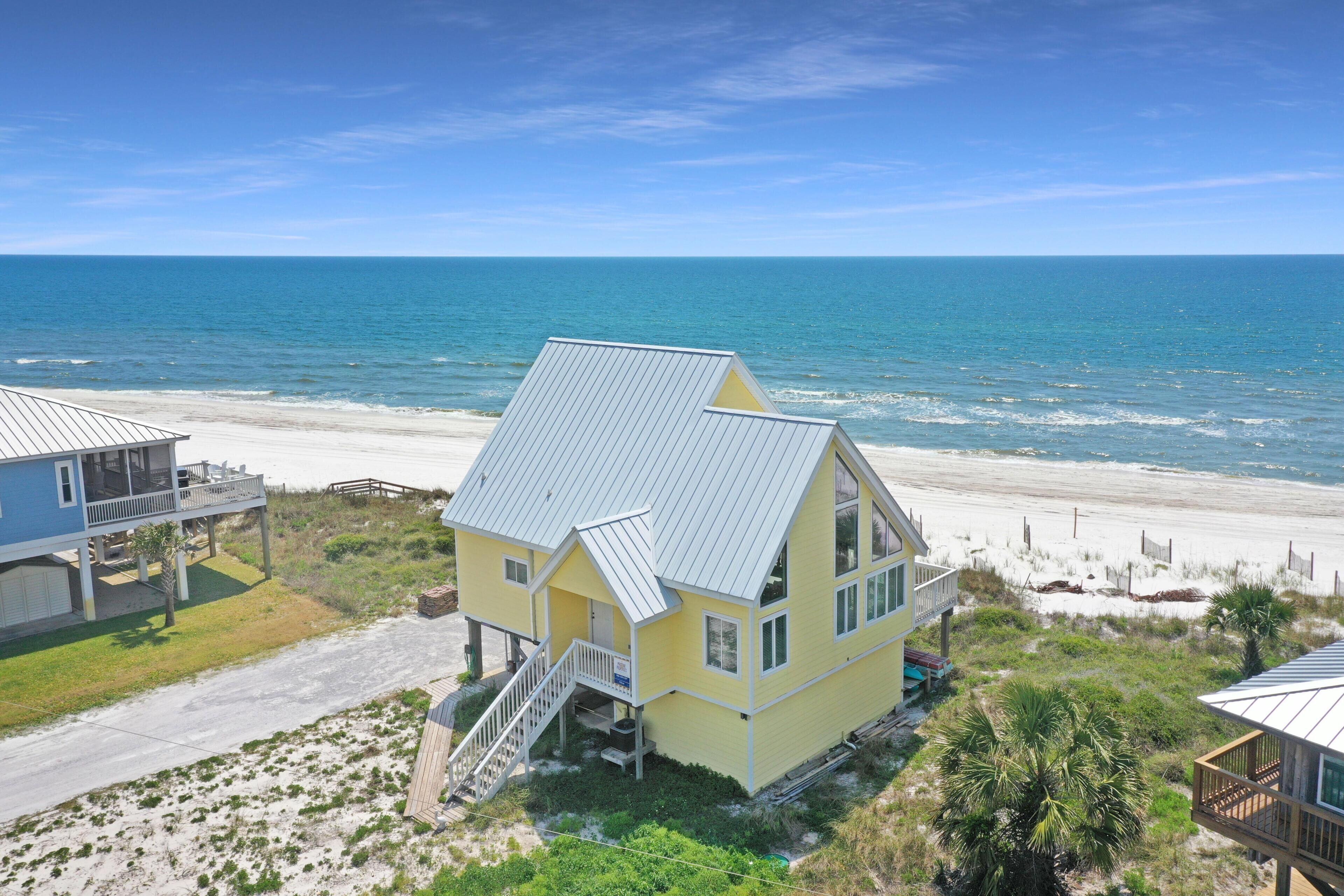 A coastal house with a balcony, a staircase, and a view of the ocean.