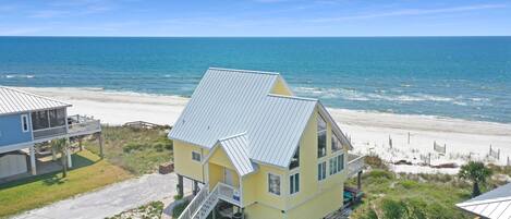 A coastal house with a balcony, a staircase, and a view of the ocean.