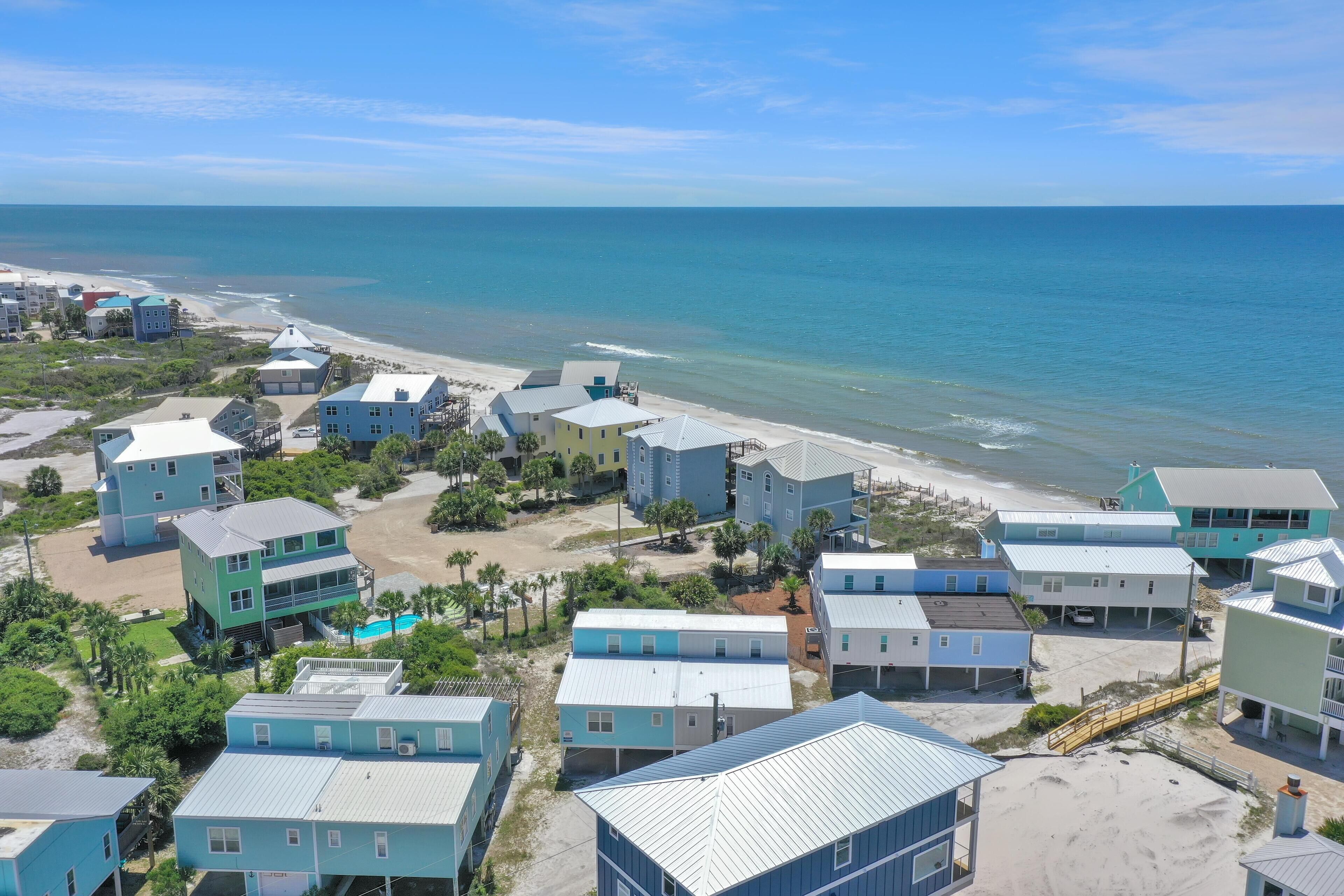 A coastal residential area with multiple two-story houses, a beach, and a clear view of the ocean.