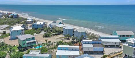 A coastal residential area with multiple two-story houses, a beach, and a clear view of the ocean.