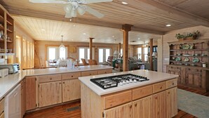 Una cocina amplia con armarios de madera, una isla central con estufa y un ventilador de techo.