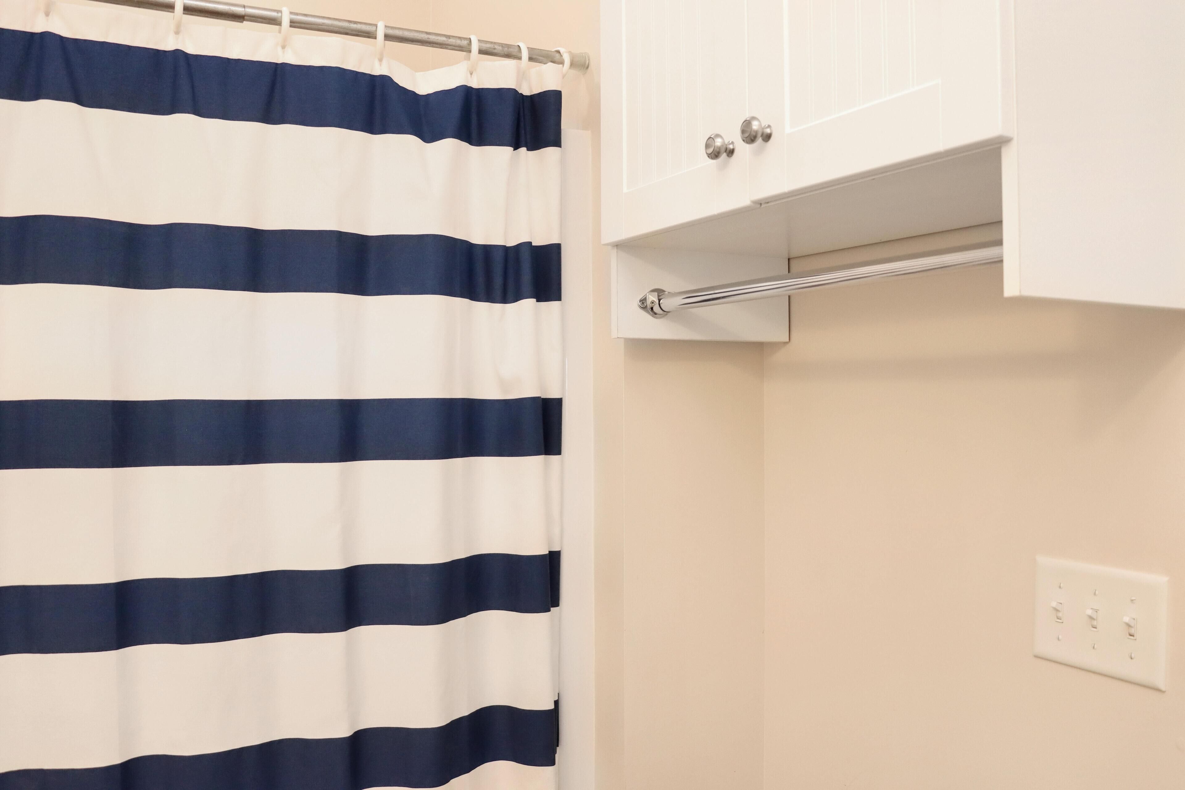 A bathroom with a striped shower curtain, a white cabinet, and a towel rack.