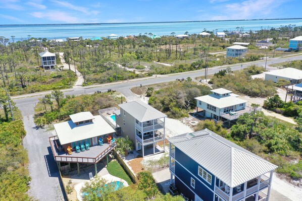 A coastal property with multiple buildings, a swimming pool, and a road leading to the beach.